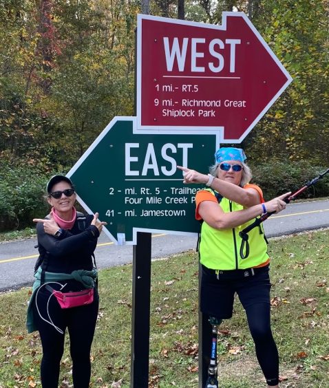 Two walkers pointing at the East and West Capital Trail signs